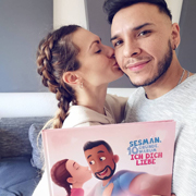 Ein sich küssendes, verliebtes Pärchen macht ein Selfie mit ihrem personalisierten Liebesbuch von Hurra Helden.